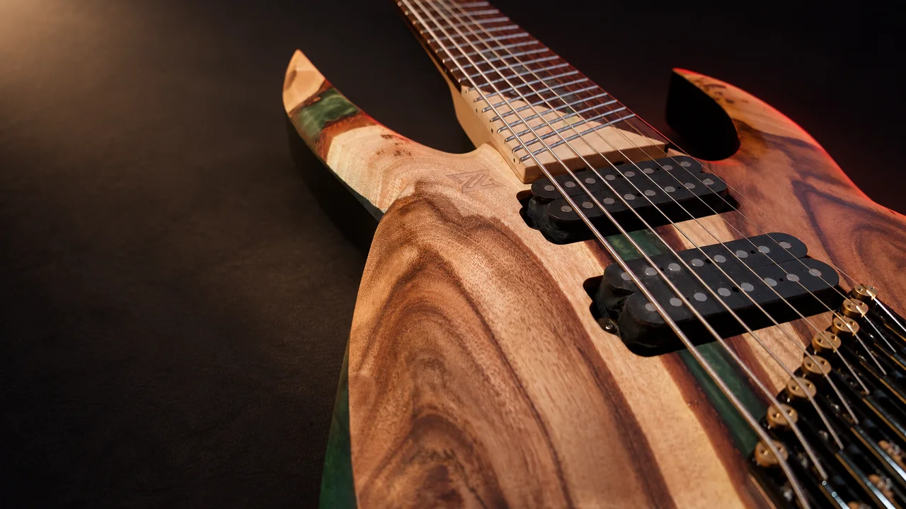 A Llamas guitar with green-accented wood, in low studio light